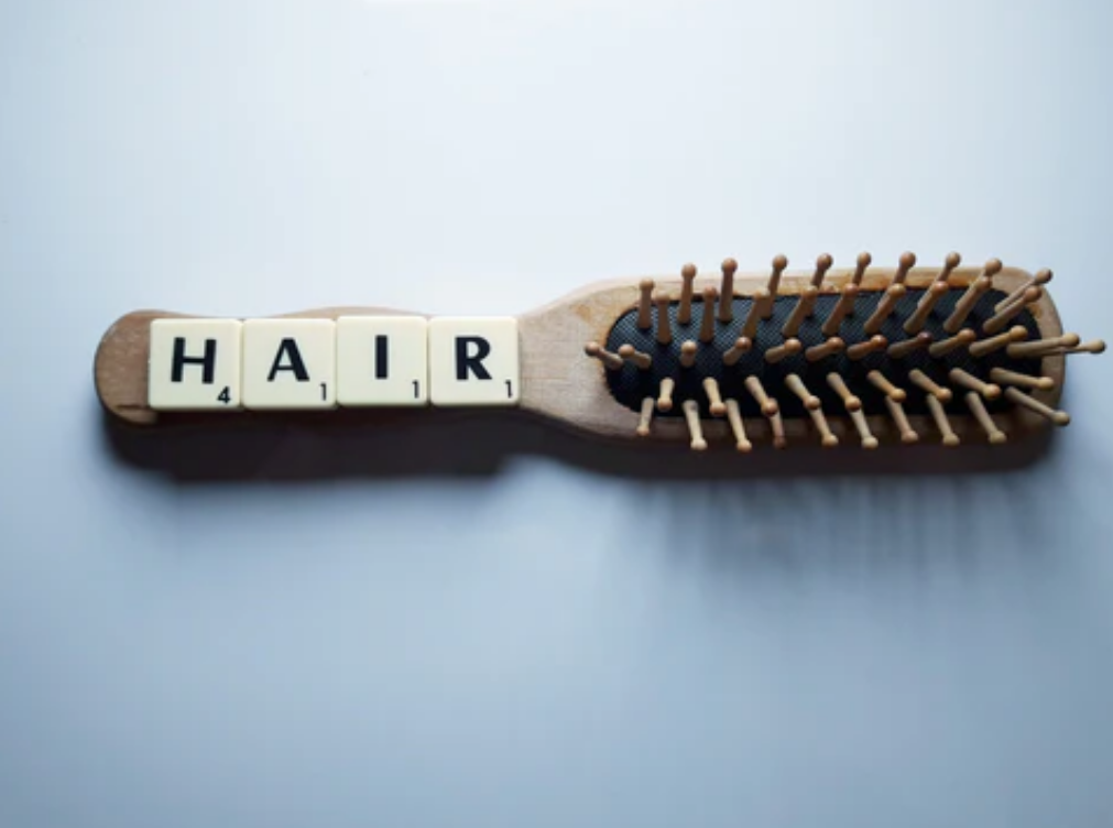 A hair brush with scrabble letters spelling out "hair". Concept of hair loss, thinning hair.